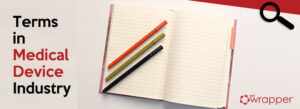 Top-down view of an open lined notebook with three colored markers and a magnifying glass icon, titled "Terms in Medical Device Industry," representing the foundational language of regulatory compliance.