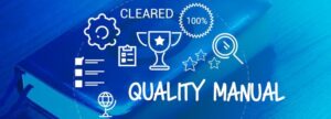 A digital overlay on a physical blue book showing "Quality Manual" with icons for 100% compliance, "Cleared" status, and a championship trophy, representing a successful ISO 13485 audit.
