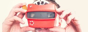 Close-up of a person looking through a classic red view-master toy with the qmsWrapper logo, symbolizing a clear vision for Quality Manual and workflow process integration.