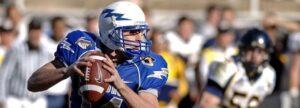 A professional American football quarterback in a blue and white uniform preparing to make a play, symbolizing the strategic coordination and team-based compliance necessary for ISO 13485 certification.